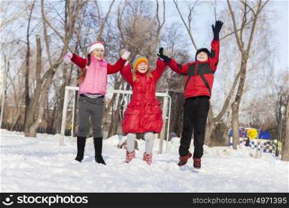 Cute children jumping and having fun in winter park. Winter activities