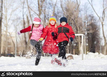 Cute children jumping and having fun in winter park. Winter activities