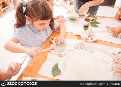 Cute children sculpt something from grey plasticine in kindergarten. Happy children are engaged with modeling clay