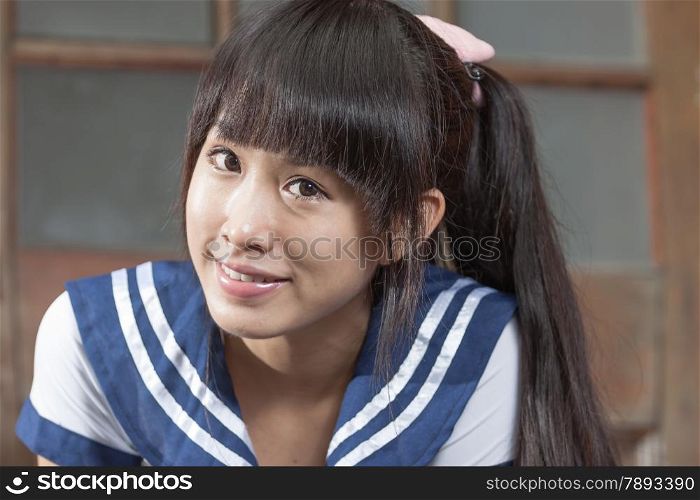 Cute Chinese schoolgirl in front of brown door school building