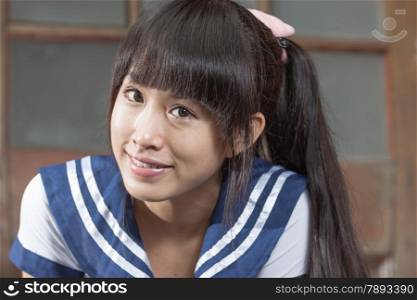 Cute Chinese schoolgirl in front of brown door school building