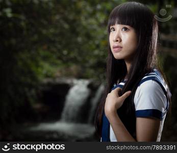 Cute Chinese schoolgirl with waterfall in background