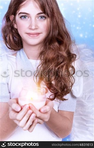 Cute Christmas angel on blue snowy background, adorable girl with candle in hands, religious winter holiday, peace and harmony concept