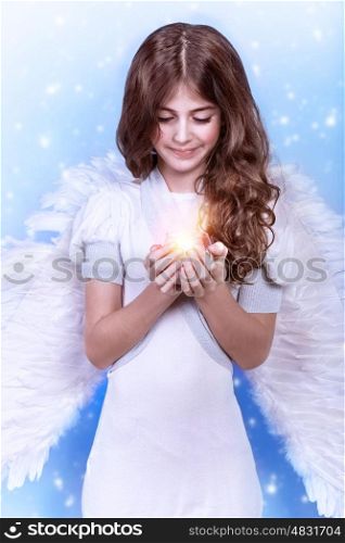 Cute Christmas angel on blue snowy background, adorable girl with candle in hands, religious winter holiday, peace and harmony concept