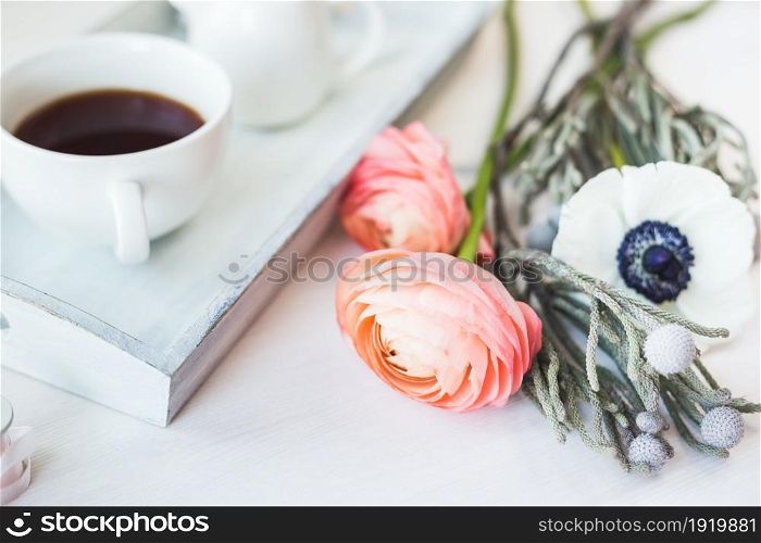 Cute close-up photo of a coffee cup on a tray with flowers.. . Cute vintage mock up on wooden background. Flat lay top view.