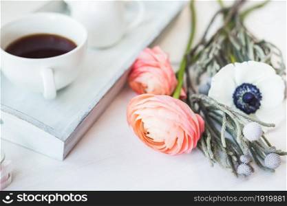 Cute close-up photo of a coffee cup on a tray with flowers.. . Cute vintage mock up on wooden background. Flat lay top view.