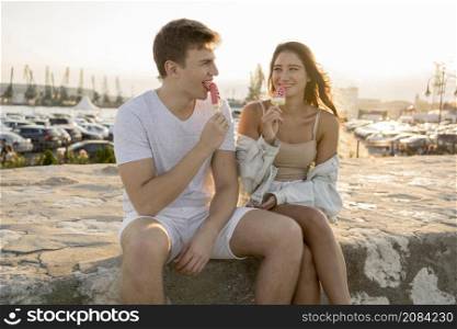 cute couple eating popsicles outdoors sunset