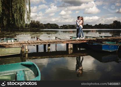 Cute couple walking near water. Girl in a white shirt. Pair by the river. Loving young couple near the river with boats. love without borders. selective focus.. Cute couple walking near water. Girl in a white shirt. Pair by the river. Loving young couple near the river with boats. love without borders. selective focus