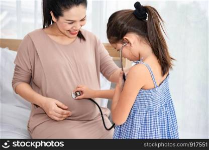 Cute daughter listening to voice or heart beat of baby in mother belly for checking new life. Pregnant and parent. Health and medical. People lifestyle and family concept. Motherhood and sister relate