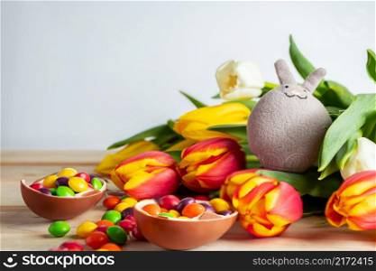 Cute easter bunny and chocolate eggs. Composition for holiday from sweets and tulips.. Easter bunny and chocolate eggs. Composition for holiday from sweets and tulips.