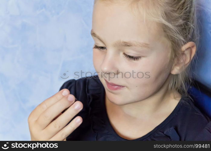 Cute eating girl with blond hair on blue background