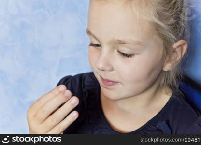 Cute eating girl with blond hair on blue background