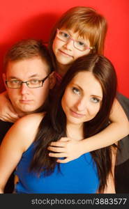 cute family of three face closeup portrait at home. Woman man and child little girl on red