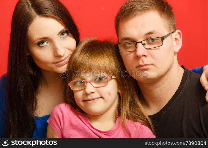 cute family of three face closeup portrait. Woman man and child little girl on red