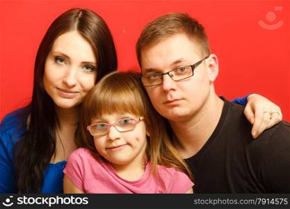 cute family of three face closeup portrait. Woman man and child little girl on red