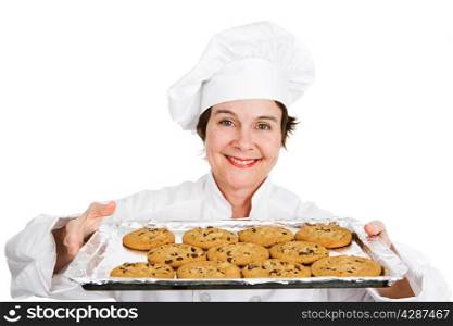 Cute female chef in her uniform, holding up a tray of delicious, freshly baked chocolate chip cookies. Isolated on white background.
