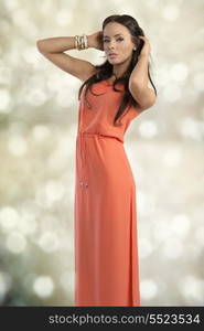 cute female with elegant style and long brown hair, wearing orange dress and bracelets, sensual pose