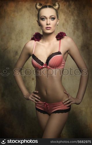 cute female with perfect body posing in creative glamour shoot with pink lingerie, stylish hairdo and red roses on the shoulders halloween concept