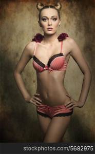cute female with perfect body posing in creative glamour shoot with pink lingerie, stylish hairdo and red roses on the shoulders halloween concept