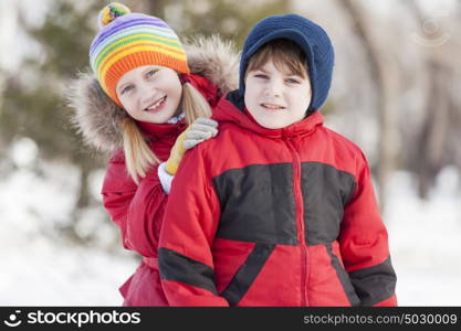 Cute girl and boy having fun in winter park. Winter activities