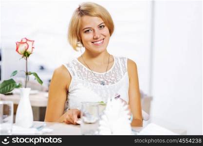 Cute girl at cafe. Portrait of young pretty woman sitting at cafe