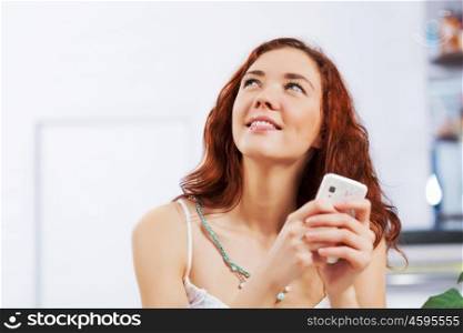 Cute girl at cafe. Portrait of young pretty woman sitting at cafe and using mobile phone