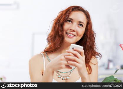 Cute girl at cafe. Portrait of young pretty woman sitting at cafe and using mobile phone