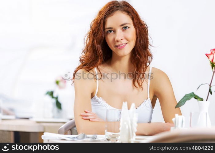 Cute girl at cafe. Portrait of young pretty woman sitting at cafe