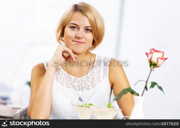 Cute girl at cafe. Portrait of young pretty woman sitting at cafe