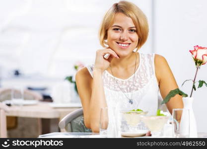 Cute girl at cafe. Portrait of young pretty woman sitting at cafe