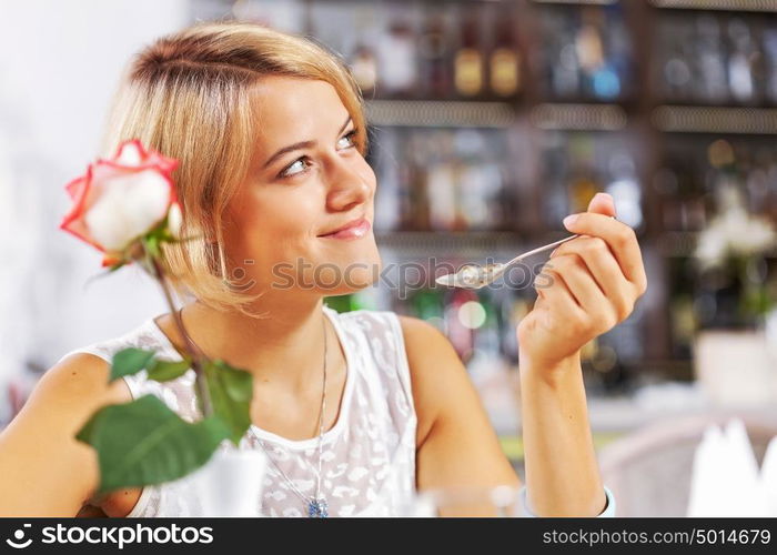 Cute girl at cafe. Portrait of young pretty woman sitting at cafe and eating dessert