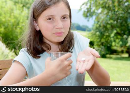 cute girl child taking pill with glass of water