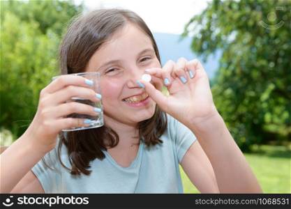 cute girl child taking pill with glass of water