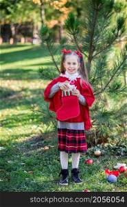 Cute girl decorating the Christmas tree outdoors in the yard before the holidays. Merry Christmas and happy holidays.. Cute girl decorating the Christmas tree outdoors in the yard before the holidays.