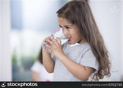 Cute girl drinking glass of water at home