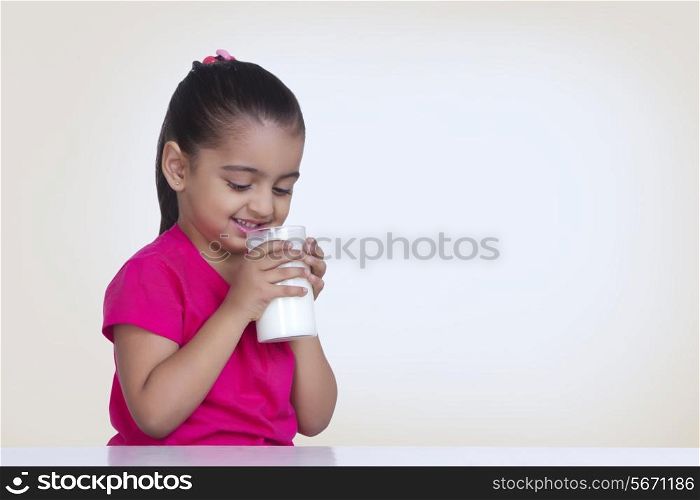 Cute girl drinking milk against colored background