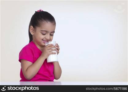 Cute girl drinking milk against colored background
