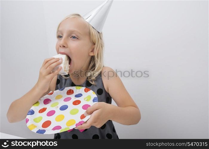 Cute girl eating birthday cake slice at home