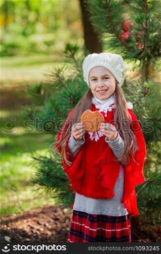 Cute girl eating Christmas cookies on a background of the New Year tree. Winter holidays and people concept. Merry Christmas and happy holidays.. Cute girl eating Christmas cookies on a background of the New Year tree.