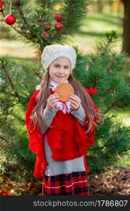 Cute girl eating Christmas cookies on a background of the New Year tree. Winter holidays and people concept. Merry Christmas and happy holidays.. Cute girl eating Christmas cookies on a background of the New Year tree. Winter holidays and people concept.