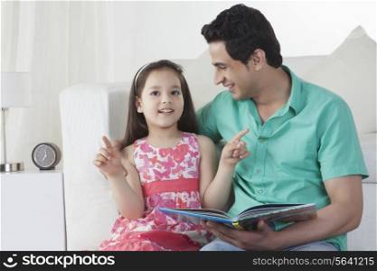 Cute girl explaining story to father on sofa at home
