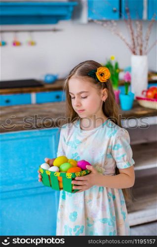 Cute girl holding basket with painted eggs. Cooking in the kitchen for the holiday Easter.. Cute girl holding basket with painted eggs.