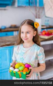 Cute girl holding basket with painted eggs. Cooking in the kitchen for the holiday Easter.. Cute girl holding basket with painted eggs.
