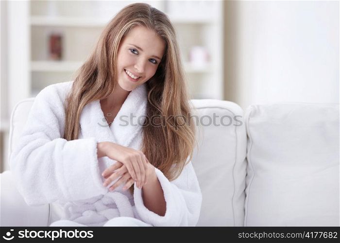 Cute girl in a bathrobe rubs his hands with cream