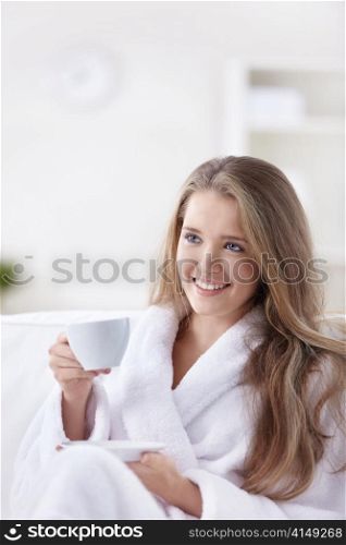 Cute girl in a bathrobe with a cup