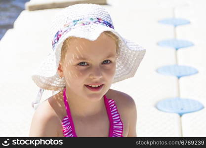 Cute girl in pink swimsuit and white hat