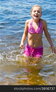 Cute girl in pink swimsuit bathing in the sea