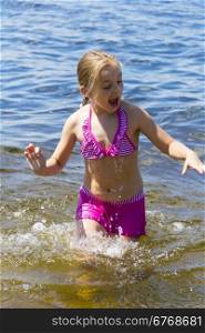 Cute girl in pink swimsuit bathing in the sea