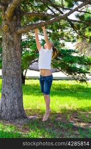 Cute girl in summer try to jump on tree