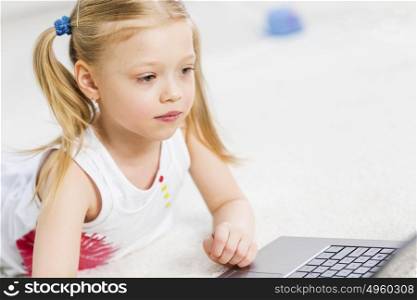 Cute girl laying on the floor and play at laptop. My favourite game